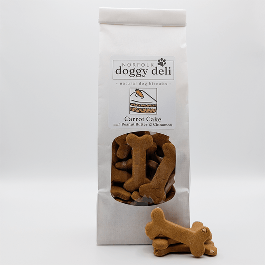 Bag of Norfolk Doggy Deli Carrot Cake dog biscuits with a single biscuit in front on a white background